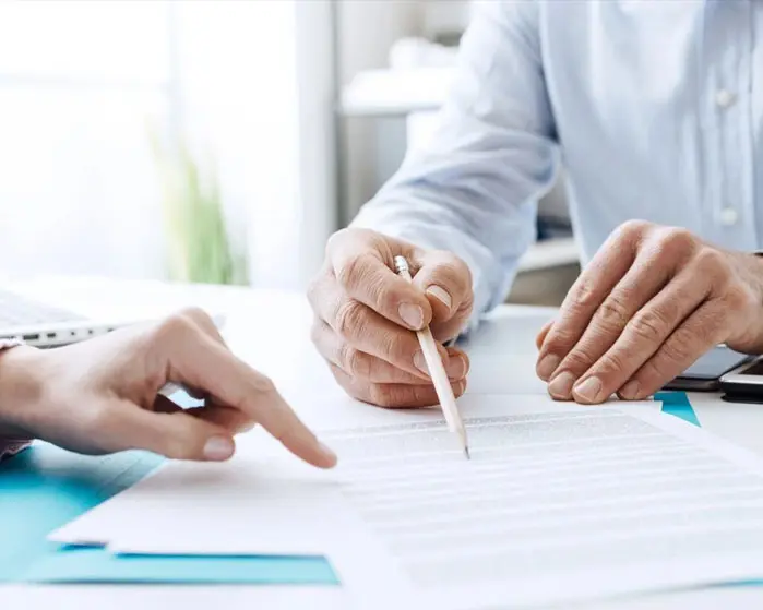 Two people are sitting at a table and one is holding a pencil