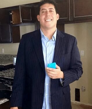 A man in a suit holding a blue object.