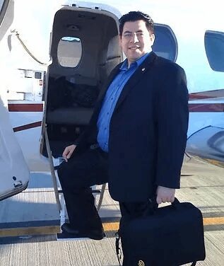 A man in a suit and tie standing next to an airplane.